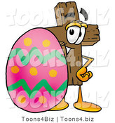 Illustration of a Cartoon Christian Cross Mascot Standing Beside an Easter Egg by Mascot Junction